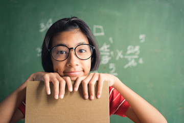 Asian  little girl smiles and hold  a book in her hand and is using her thoughts in the classroom, Education  lifestyle concept