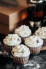 Fresh cupcakes stand on a dark table