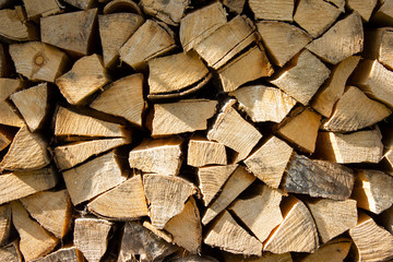 Close up of chopped pine firewood logs stacked against a wall seen front on.