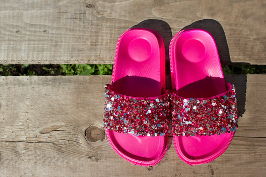 Pink flip flops with shiny rhinestones on an old piece of wood. Place under the text. Summer vacation design concept.