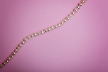 Pearl beads and a few beads are on a pale pink background. Flatlay