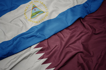 waving colorful flag of qatar and national flag of nicaragua.