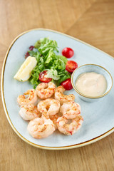 Delicious fresh seafood shrimp with fresh vegetables and lime. Plate on wooden table. Cream sauce