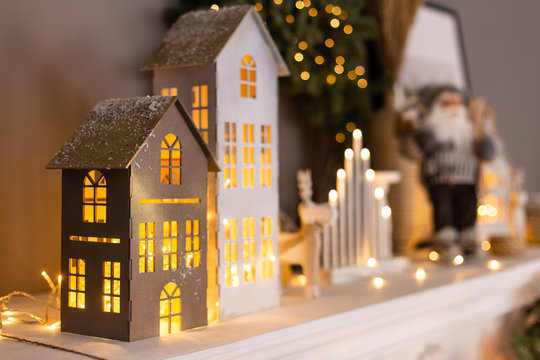 Closeup of paper houses with lights inside standing on background of other decorations. Selective focus