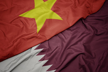 waving colorful flag of qatar and national flag of vietnam.