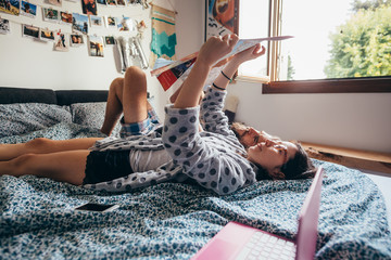 Young couple lying on bed planning travel reading map