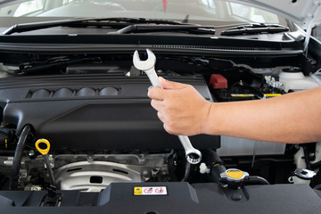 Car service concept, Mechanic Hand Hold Spanner Tool man checking the condition of car engine.