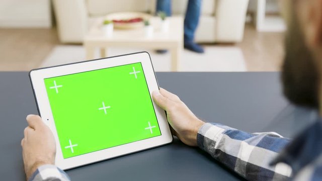 Over The Shoulder Shot Of Man Holding A Tablet With Green Screen