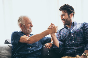 An adult son and senior father indoors at home  making fist bump.