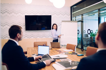 Businesswoman showing plan on flipchart in meeting room