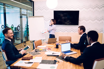 Group of smiling colleagues sharing ideas in meeting room