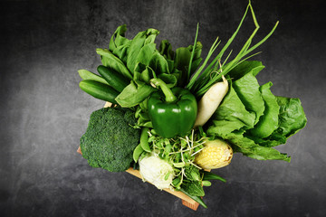 Fresh green fruit and green vegetables mixed in wooden box for sale at market , top view various for healthy food vegan cook / Harvest vegetables healthy food selection clean eating health