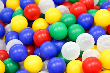 Pool with bright colorful plastic balls on kids playground. White, blue, yellow, red, green balls. Entertainment toys for happy children.