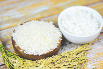 Thai rice white on bowl wooden background - raw and cooked jasmine rice grain with ear of paddy agricultural products for food in Asian