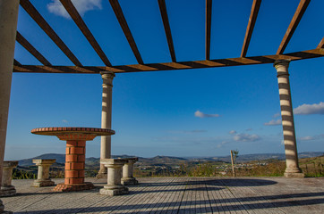 A place to relax on a hill overlooking the houses below. Table and chairs made of stone, roof,...