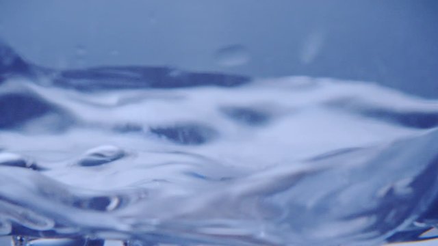 Closeup slowmotion of a clear water surface with bubbles