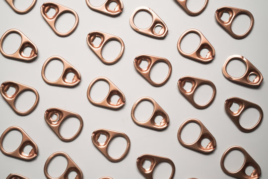 pattern of rose gold pull tab lid or ring pull on white background , recycle, reuse and environment concept