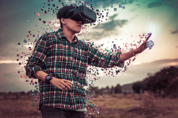 Asian man in tartan shirt wearing glasses of virtual reality dissolving into pixels on outdoor....