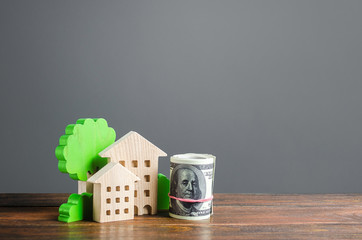 House figurines and a bundle roll dollars. Residential building maintaining cost, utility bills....