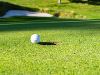 Golf course putting green with golf ball. Golf course with a rich green turf beautiful scenery.