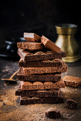 Mix stack of bitter and milky porous airy chocolate on dark old background. Selective focus.