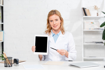 smiling nutritionist pointing with pen at digital tablet in clinic