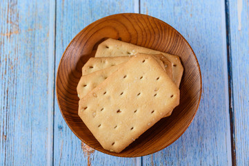 Stack many types of cookies on a plate and put on a wooden table.