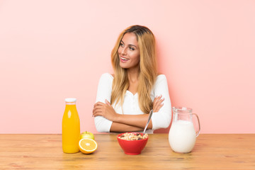Young blonde woman having breakfast milk looking to the side