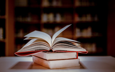Stack of books in the library and blur bookshelf background