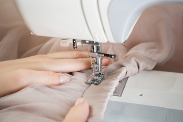 a young woman sews a dress on an electric sewing machine