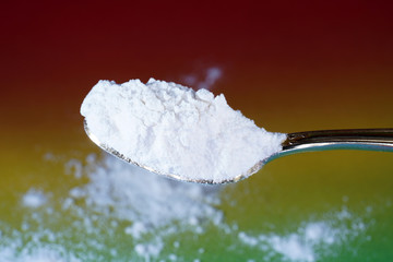 Flour that should look like a white drug with macro lens photographed in front of colorful gradient in the studio