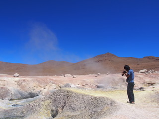 A tourist taking a picture of Sol de Mañana, Sol de Mañana (Morning Sun) is an active geothermal field, A geyser that smells of sulfur, Journey from San Pedro de Atacama in Chile to Uyuni in Bolivia