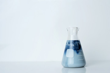 creamy opaque blue green solution in science glass flask in chemistry laboratory background