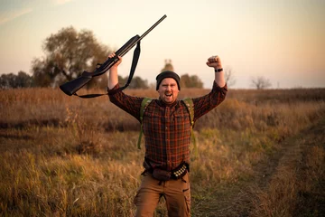 Foto op Canvas Young irish looking red bearded hunter with shotgun in his hand celebrating successful hunt on the countryside track beautifil autumn day © honey_inside