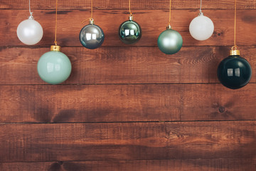 Christmas baubles hanging over wooden dark brown wall. New Year and Christmas background concept. Copy space, ball, snowflake