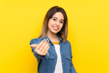 Fototapeta na wymiar Young woman over yellow background inviting to come