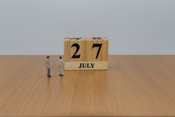 July 27, a calendar photo from the wood The table top consists of a book and pen that is ready to use. White background