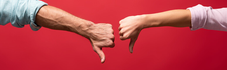 partial view of couple showing thumbs down, isolated on red
