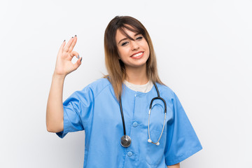 Young nurse woman over white wall showing ok sign with fingers