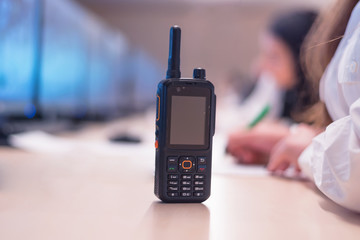 Female security guard operator talking on the phone, calling in the alarming event to the external team of field force agents.