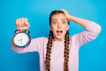 Close up photo of anxious worried youth girl with braids pigtails oversleep hold clock find she...