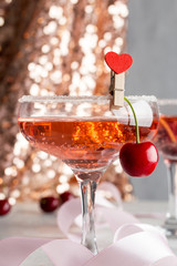 glasses with pink champagne and sweet cherry