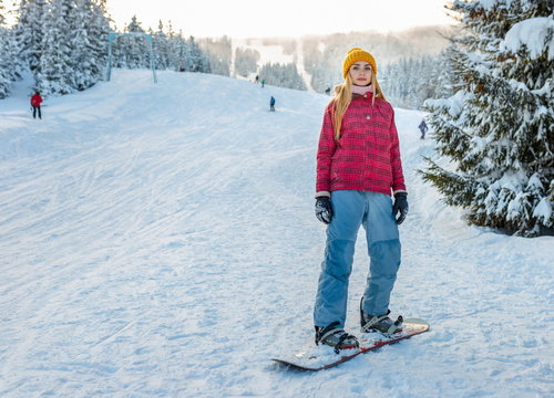 young girl snowboarding alone, winter sport activity, red ski jacket and yellow hat lifestyle