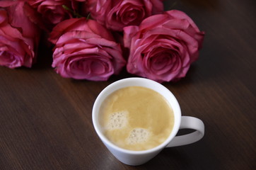 Festive mood. A bouquet of fresh fragrant pink roses for lovers and a white cup of coffee.