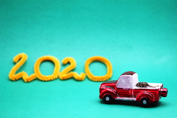 A small metal mouse on a red toy car next to the numbers 2020. The mouse is a symbol of The new year 2020 according to the Chinese calendar.