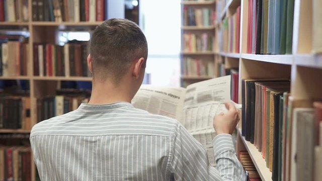 Attractive man reading a newspaper in a library