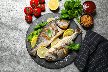 Delicious roasted fish with lemon on grey table, flat lay
