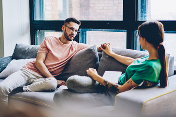 Couple in love holding hands each other and communicating spending leisure time together at home interior.Young marriage having conversation in modern apartment relaxing on comfortable sofa