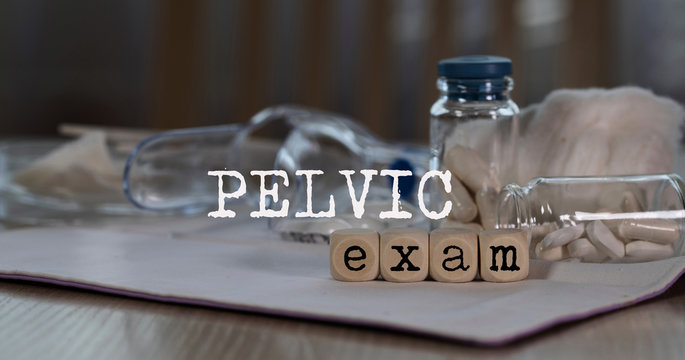 Words  PELVIC EXAM composed of wooden dices. Pills, documents and a pen in the background.