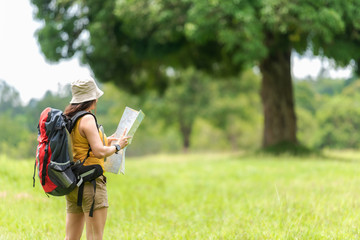 Student asian women and traveler with backpack adventure holding map to find directions location and leisure destination place in the jungle forest outdoor for study and education nature.